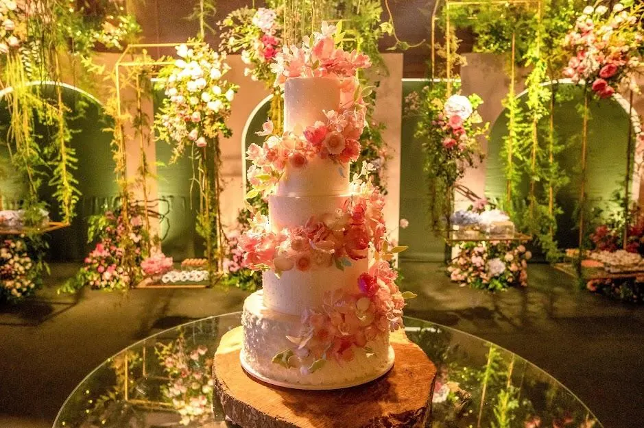 Bolo de vários andares com flores cor-de-rosa sobre base de espelho